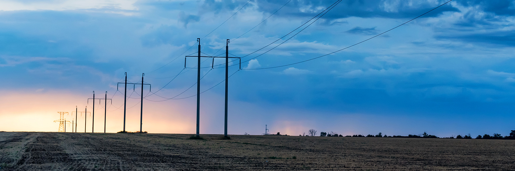 Electricity pylons extending into the distance under a twilight sky, showcasing an on-demand demo of the latest distribution design.