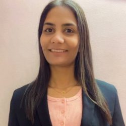 A person with long hair smiles, wearing a black blazer over a pink top, standing against a plain background, embodying the precision of OpenRoads Designer.