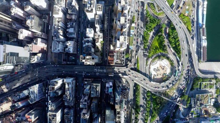 Aerial view of an urban cityscape with tall buildings, intersecting roads, and a large roundabout surrounded by greenery—perfect inspiration for CAD workflows or MicroStation 2025 design projects.